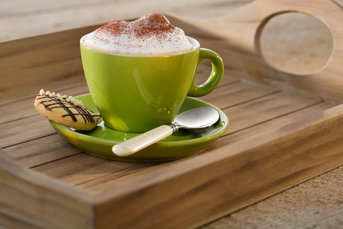 Cappuccinotasse mit Keks auf Untertasse