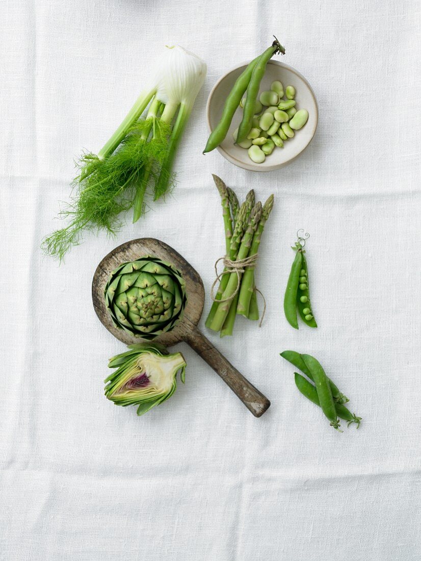 Verschiedene grüne Gemüsesorten auf weißem Tuch (Draufsicht)