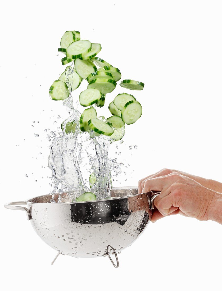 Cucumber slices being washed in a sieve