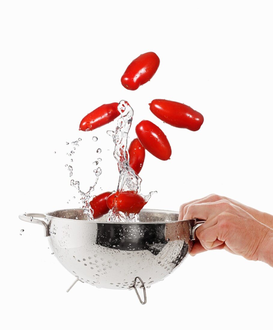 Washing baby plum tomatoes in a colander