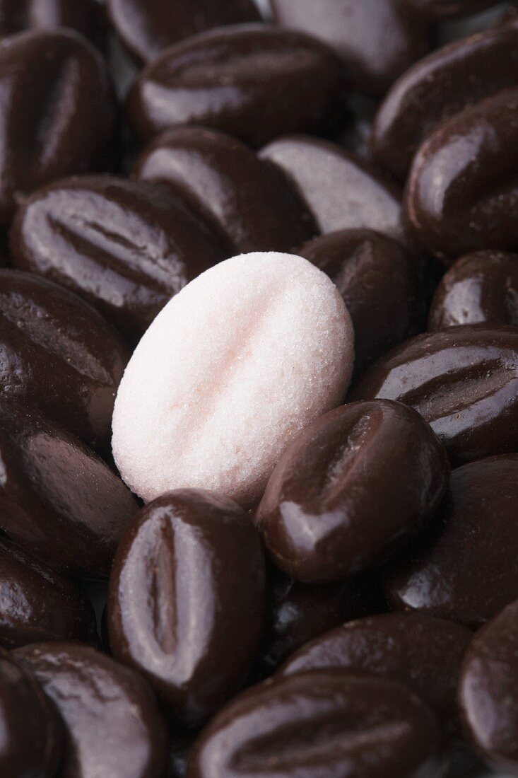A pink sugar coffee bean on a pile of real coffee beans