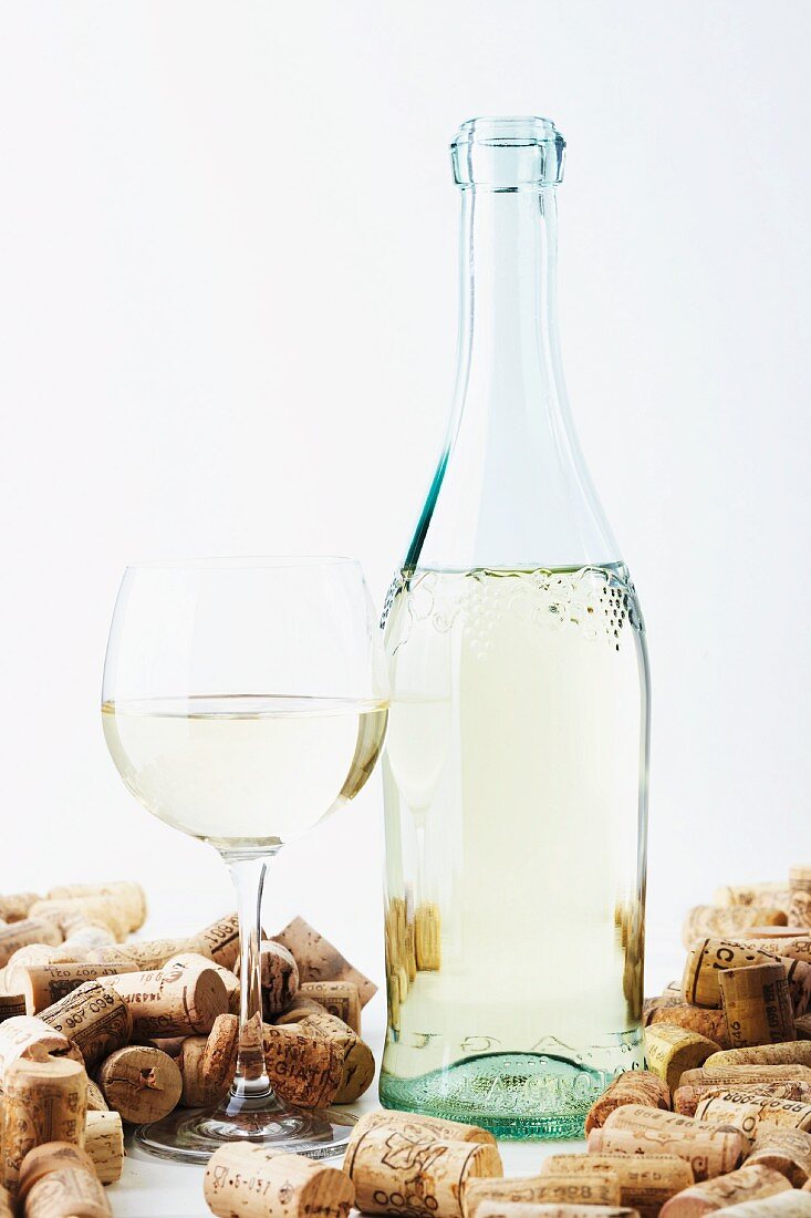 A bottle and a glass of wine with corks