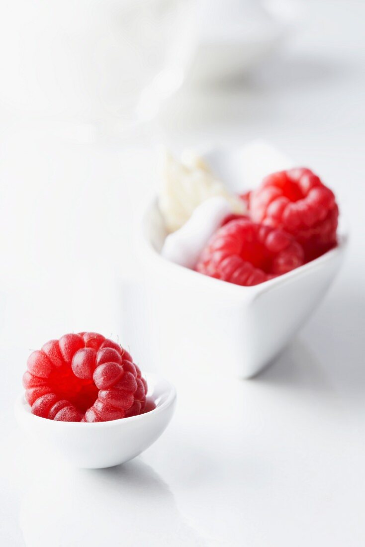 Raspberries in a bowl with cream and on a spoon