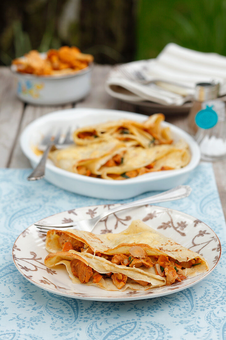 Crepes with chanterelle mushrooms on a table in a garden