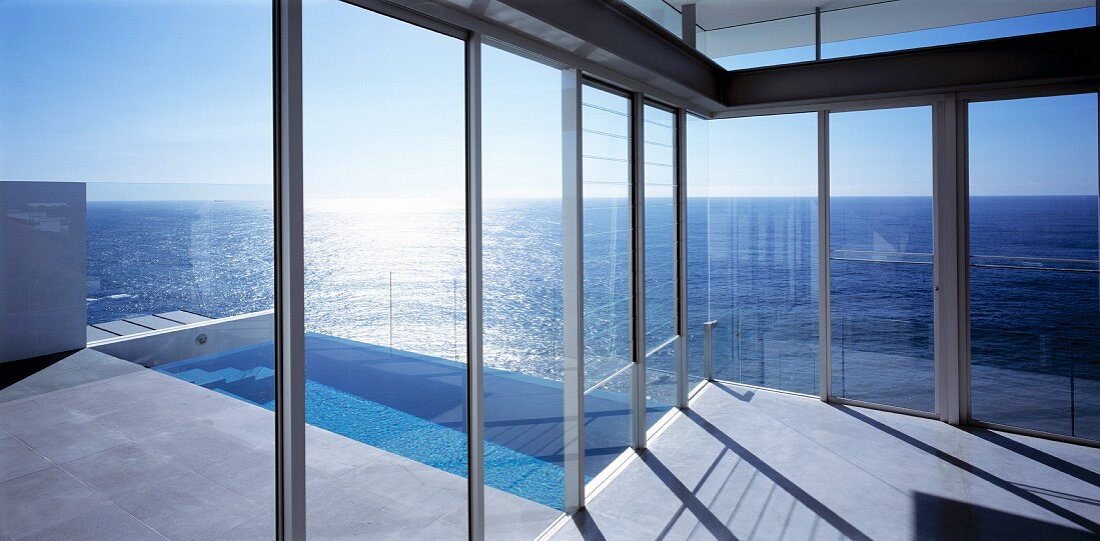 Blick durch Glaswände auf den Pool und das Meer