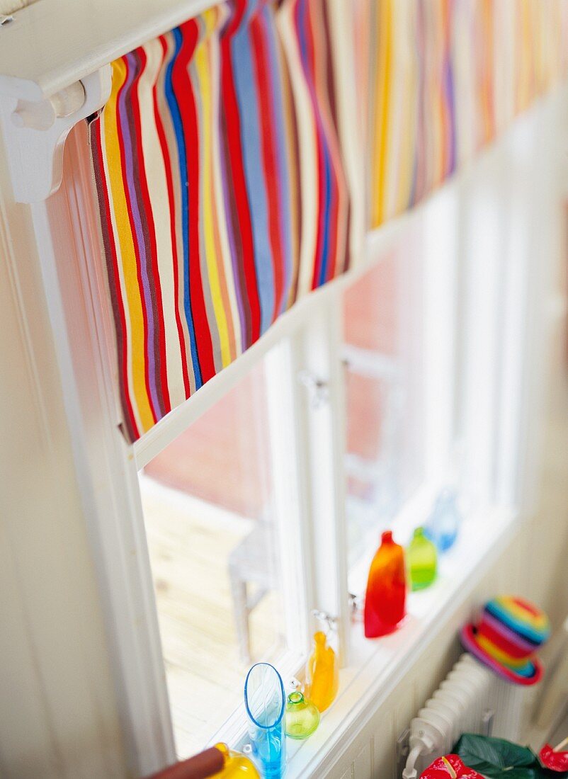 Colourful striped curtain on window, colourful vases on windowsill