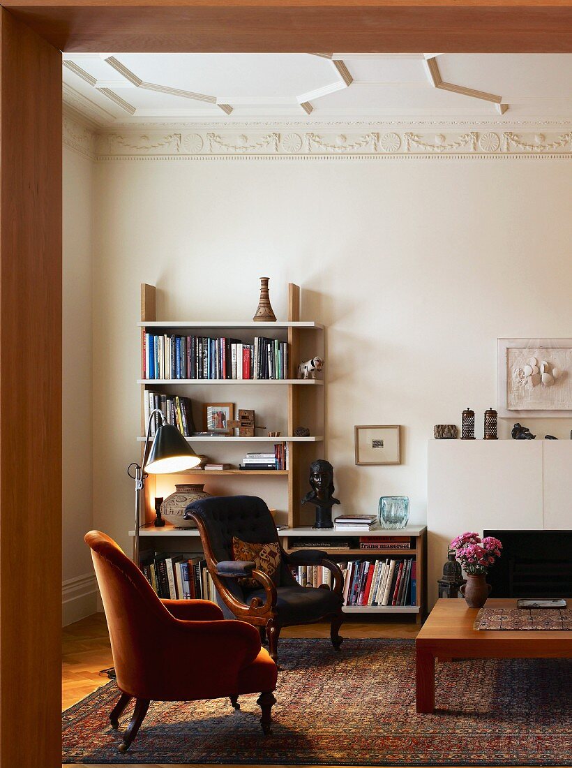 View of antique armchairs in front of modern shelving in classic living room