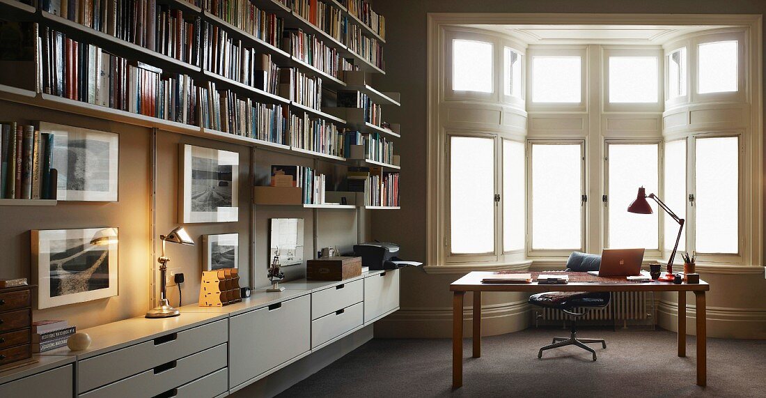Modern library with desk in front of traditional bay window