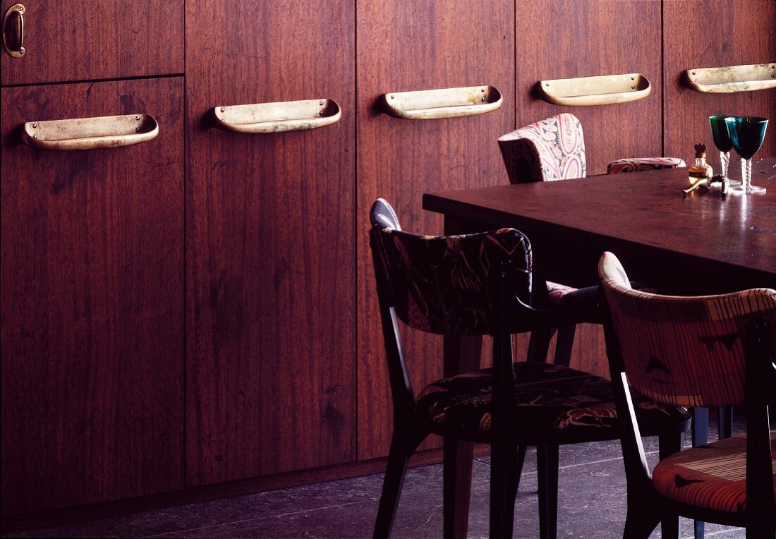 Table and chairs in front of wooden fitted cupboards