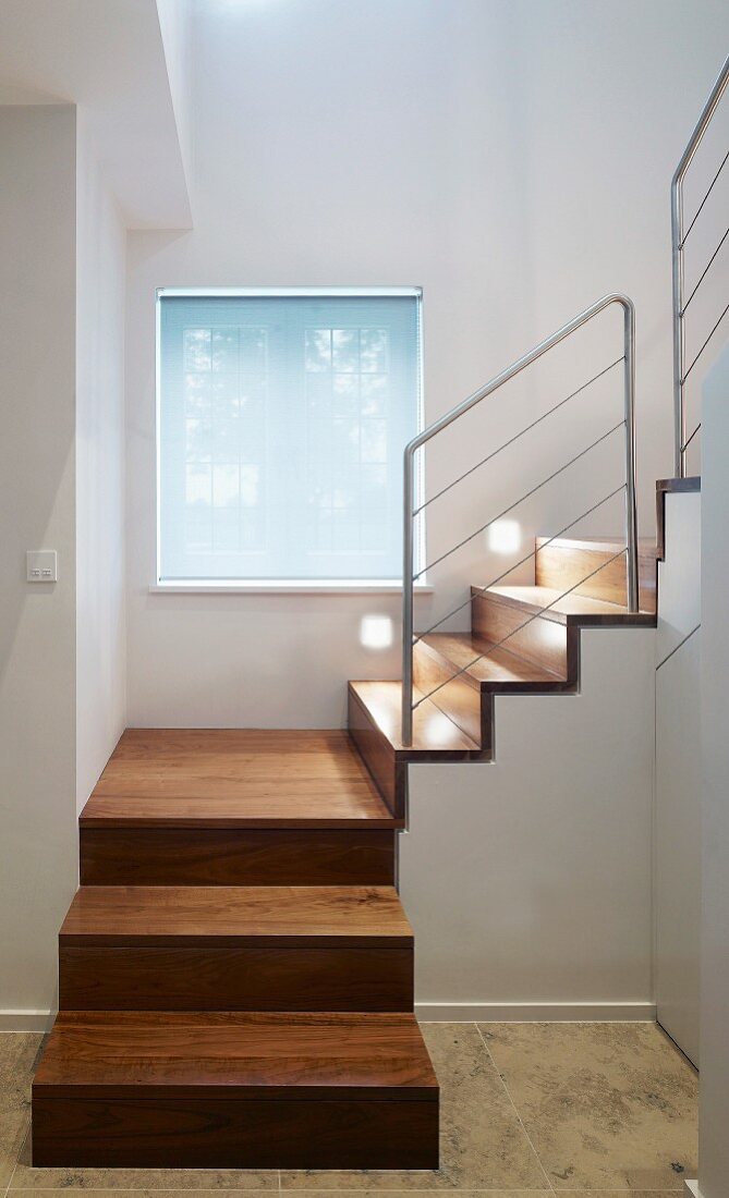 Modern stairwell with square spiral wooden staircase and stainless steel balustrade