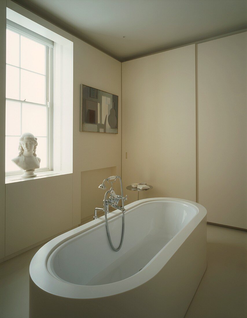 Bathroom with free-standing bathtub and bust on windowsill