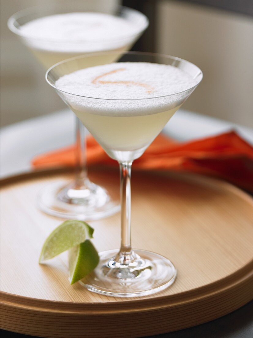 Zwei Pisco Sour Cocktails auf Holztablett