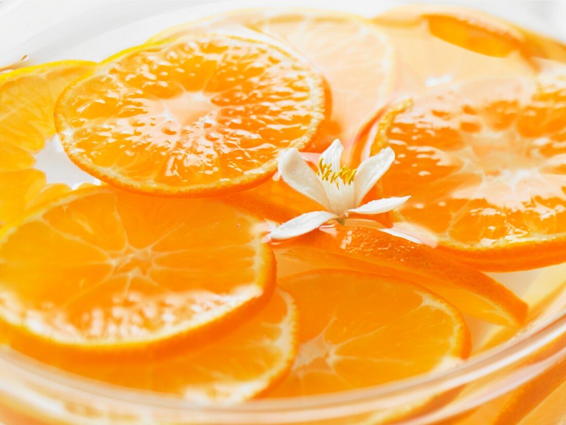 Orangenscheiben und Orangenblüte in Wasserschale