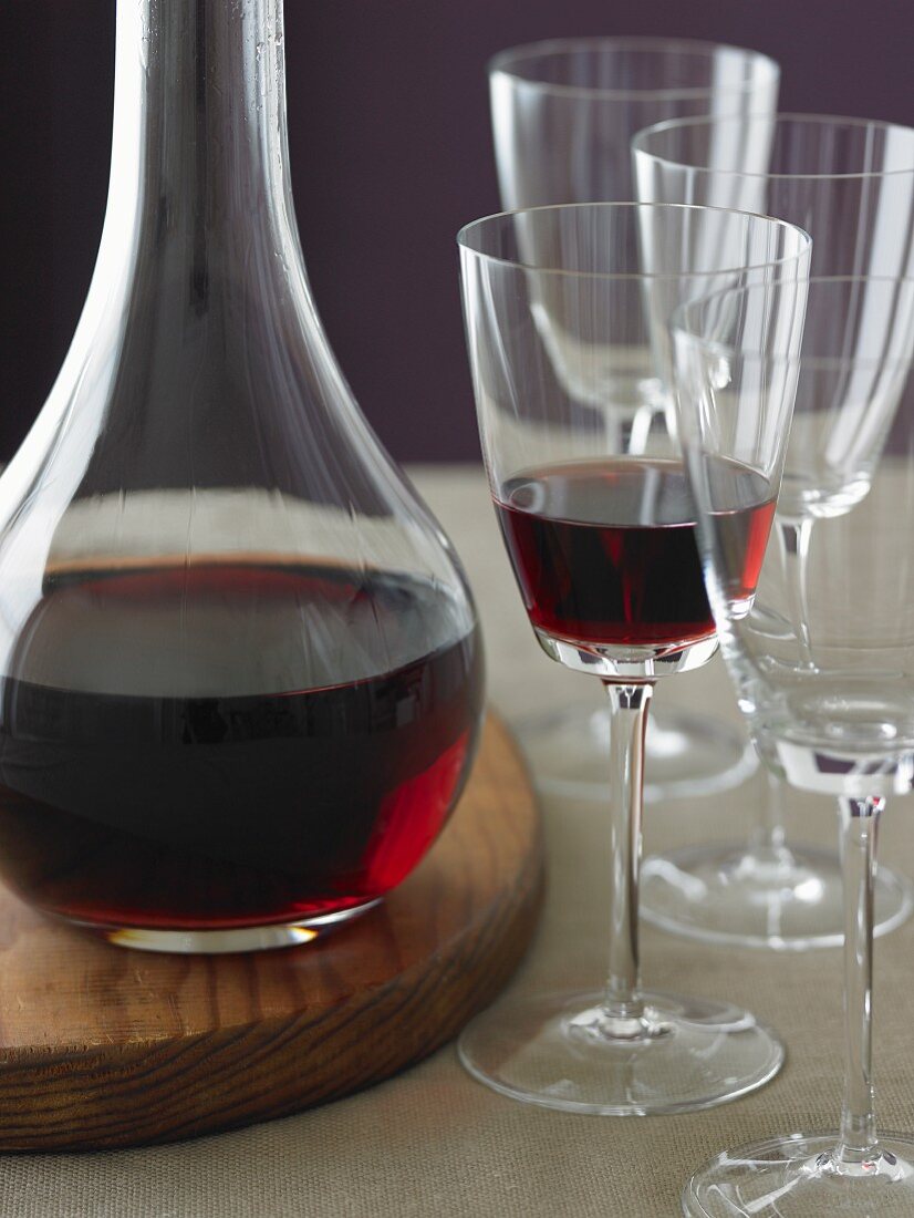 Rotwein in Karaffe und Glas, leere Weingläser