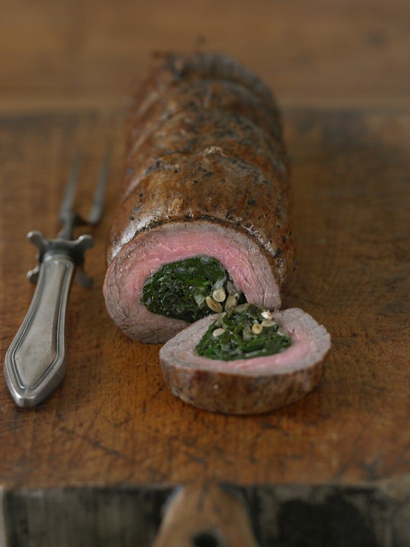 Beef Rolled and Stuffed with Spinach and Garlic; Partially Sliced on a Cutting Board