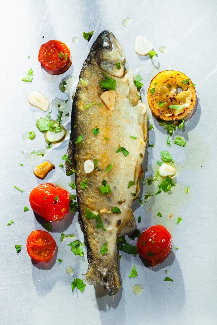 Fried trout with herbs, garlic, tomatoes and lemons