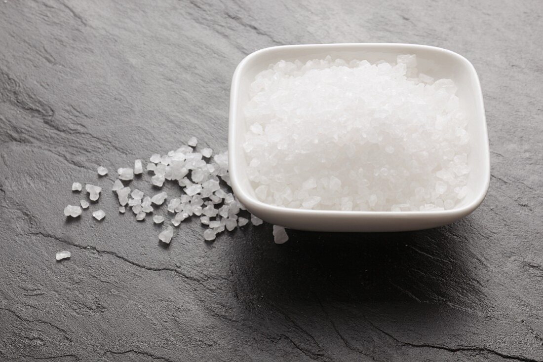 Sea salt in a bowl and on a slate surface