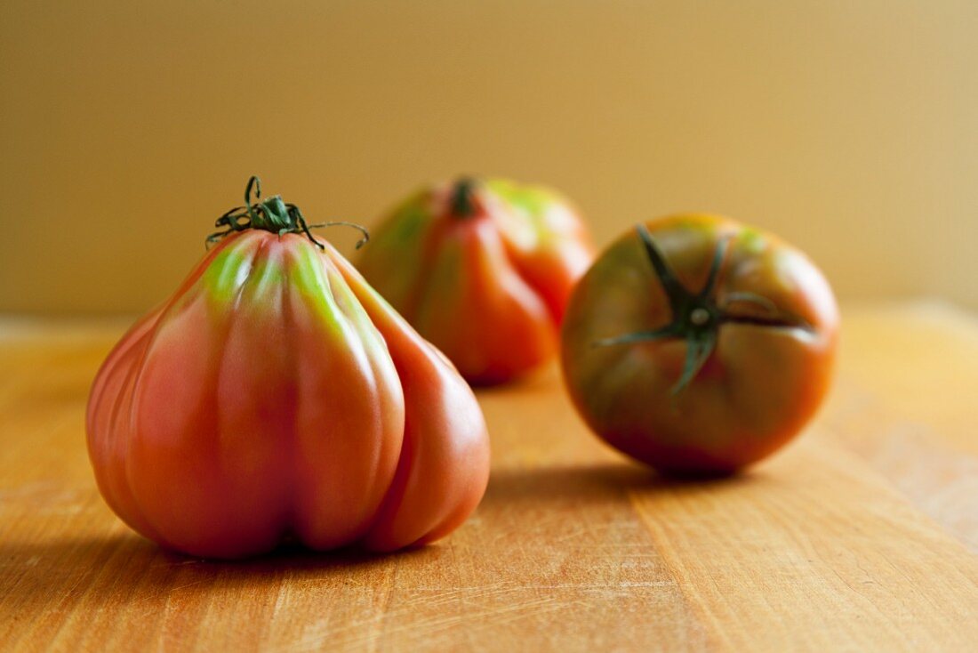 Three Fresh Ugly Tomatoes on Wooden Surface