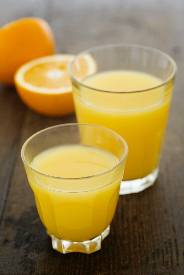 Two glasses of orange juice and fresh oranges