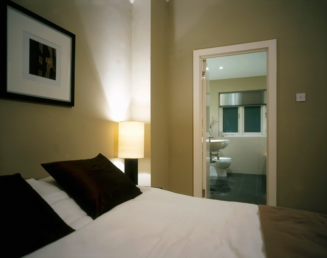 Dark pillows and picture frames in light, modern bedroom with ensuite bathroom