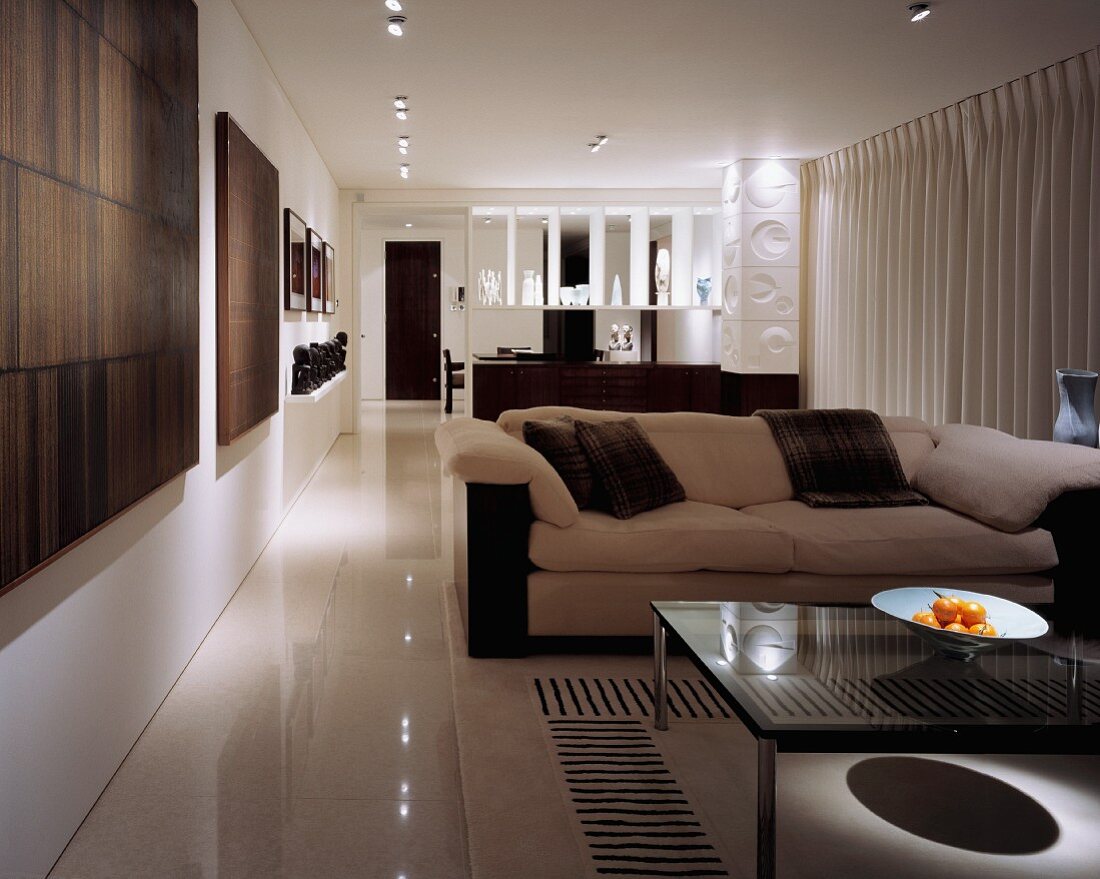 Long, open-plan living-dining room with artworks and contemporary brown and white furniture