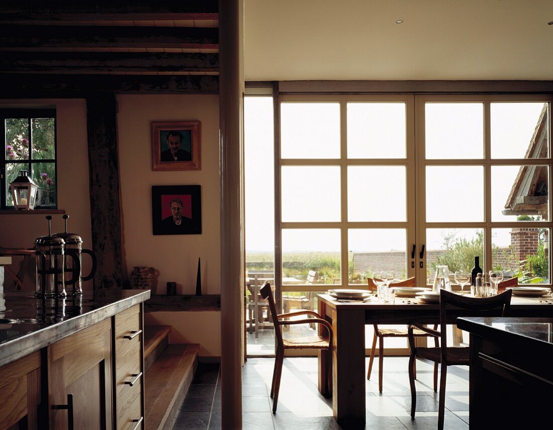 Modern kitchen-dining room with country house elements in front of wide glass wall and view of open landscape