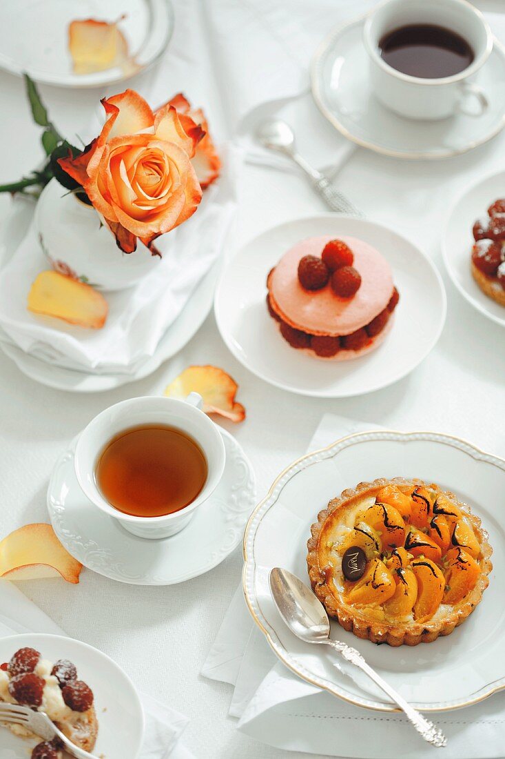 Assorted French pastries, tea and coffee on a table set in white