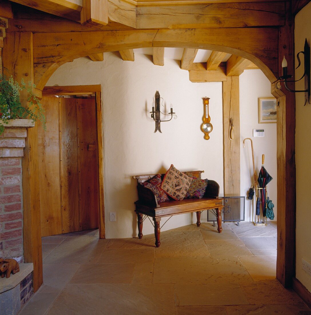 Rustic foyer with patterned cushions on antique wooden bench