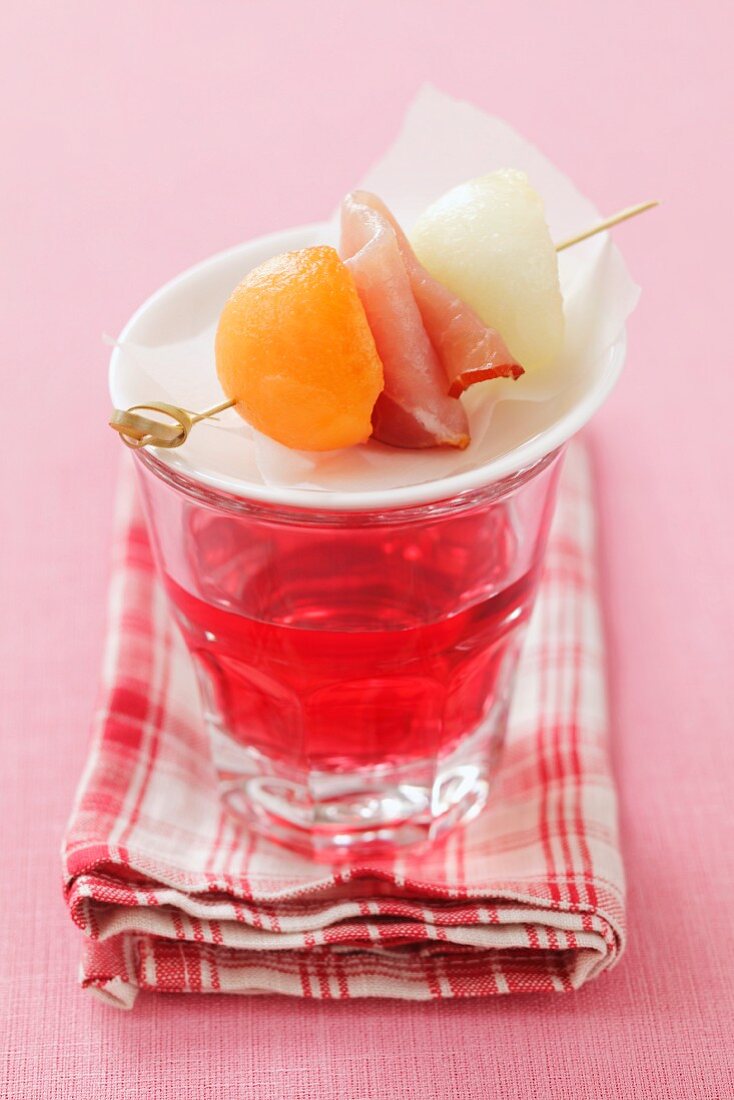 Minispiesschen mit Bacon und Melone auf einem Glas Rosewein