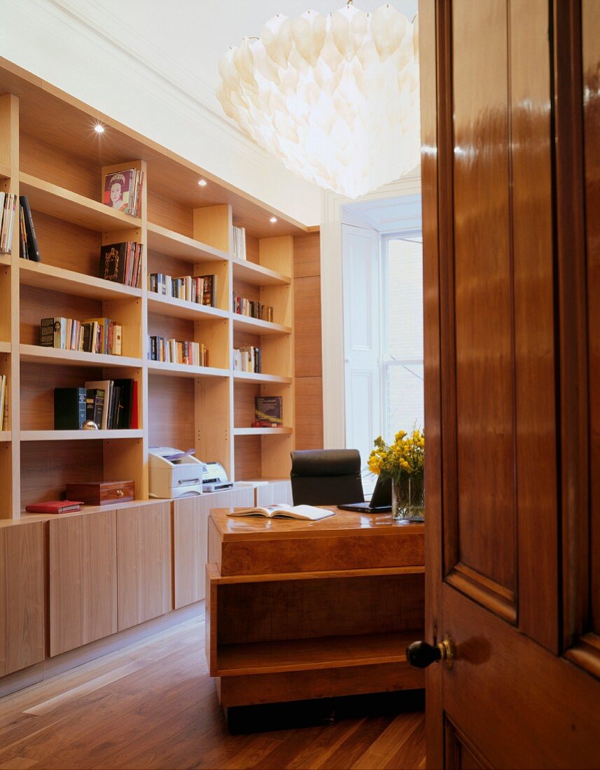 View of wooden bookcase in living room through open door