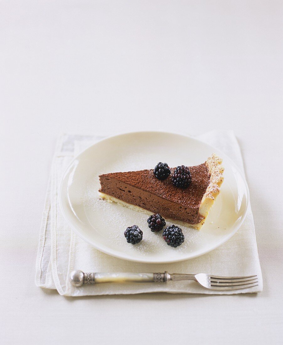 A slice of chocolate tart with blackberries