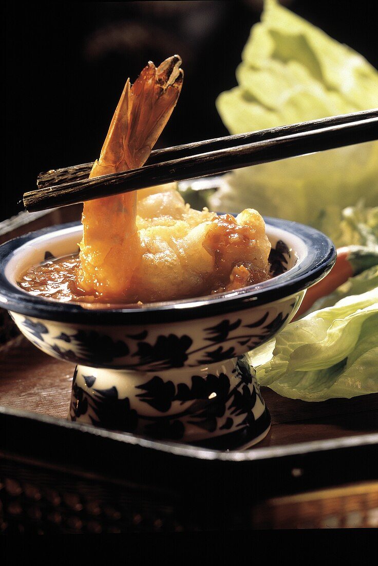 Chop Sticks Dipping a Shrimp into Cocktail Sauce