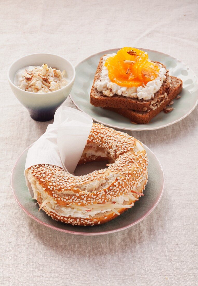 Sesame bagel with cream cheese and grated apple and wholewheat bread with cottage cheese and oranges