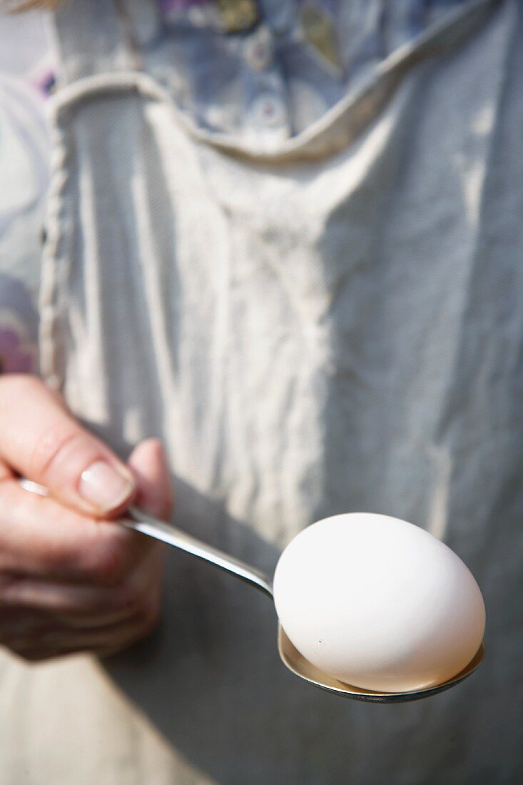 Hand holding egg on spoon