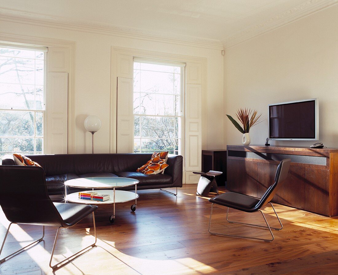 Black leather, retro armchairs and couch in living room with classic ambience