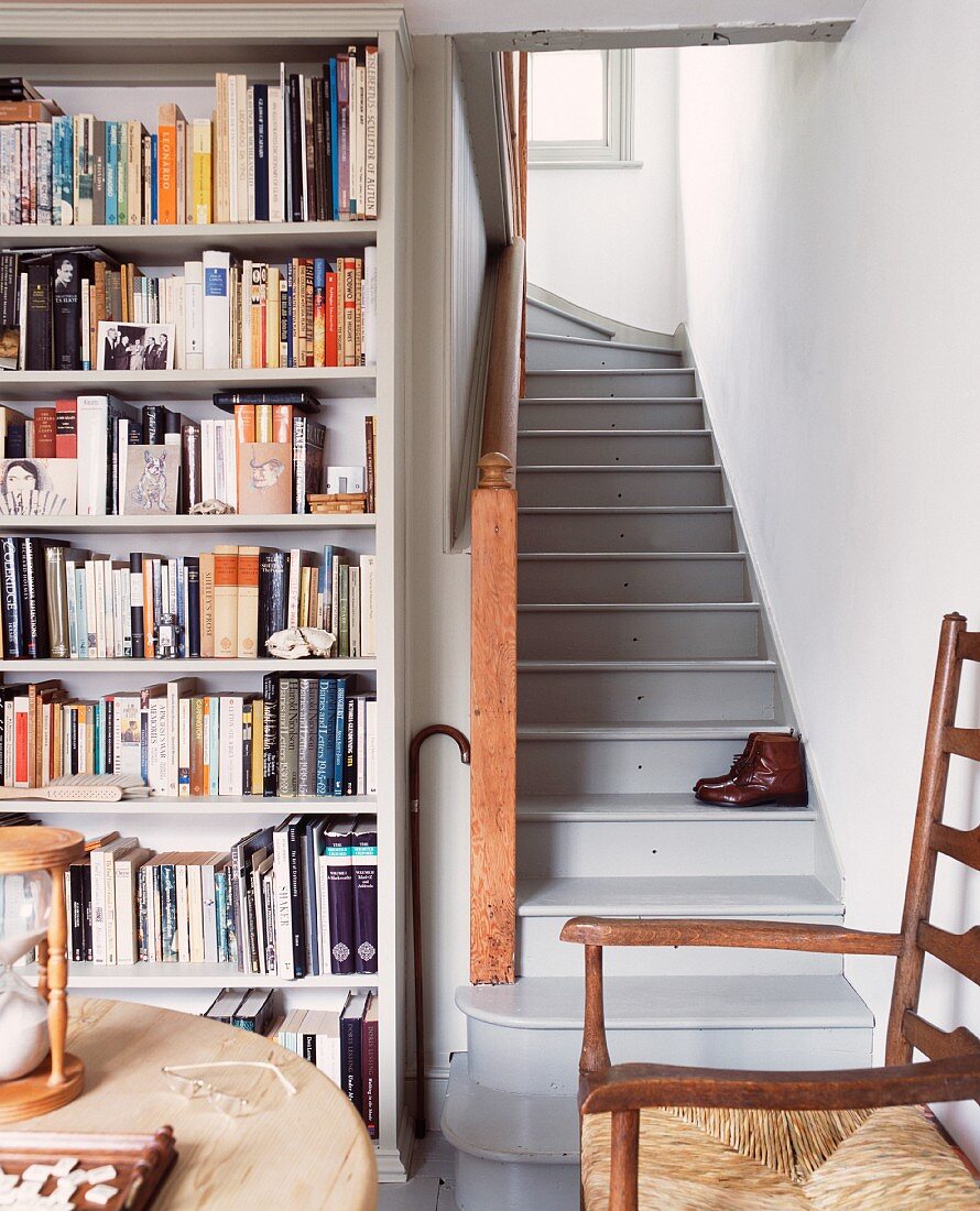 Corner of room with fitted bookcase and old, grey wooden staircase