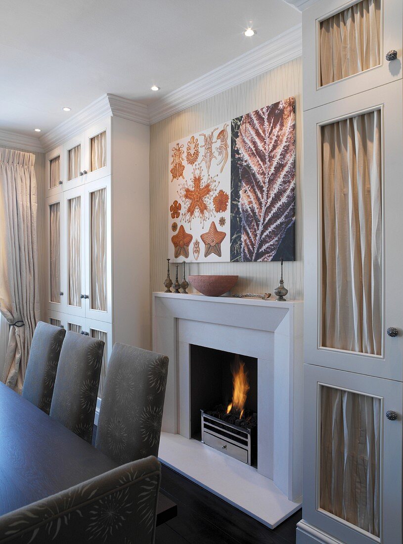 Fitted cupboards with fabric door panels on both sides of dining room fireplace