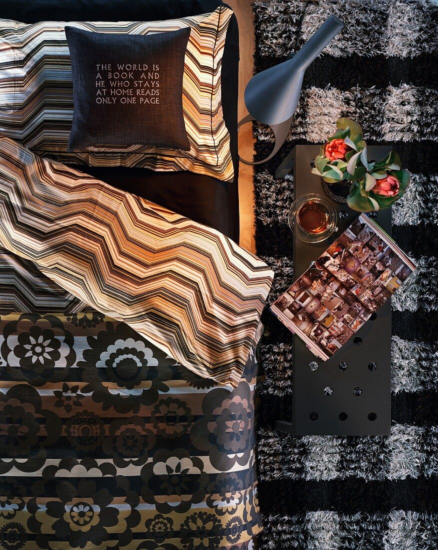 Mix of patterns in bedroom - turned down, reversible bedspread and narrow bedside table on fleecy rug