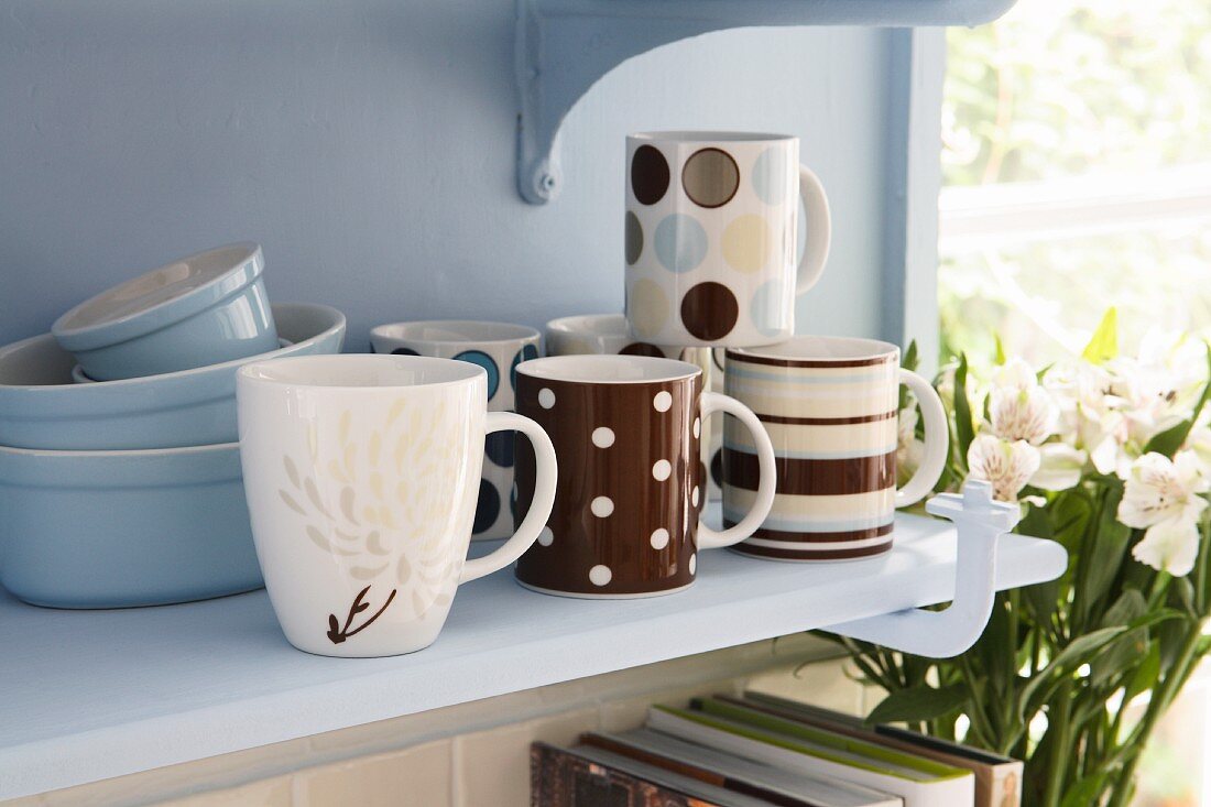 Cups and baking dishes on a shelf in a kitchen