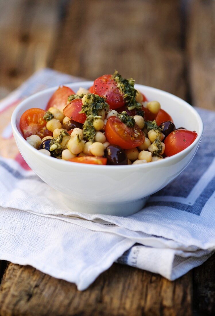 Tomato salad with chickpeas, black olives and pesto dressing