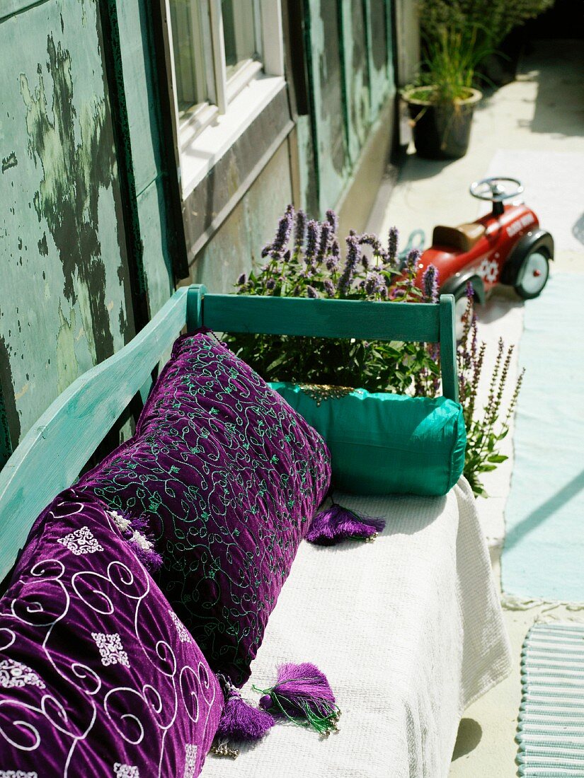Cushions made of violet velvet fabric on a wooden bench in the sunshine