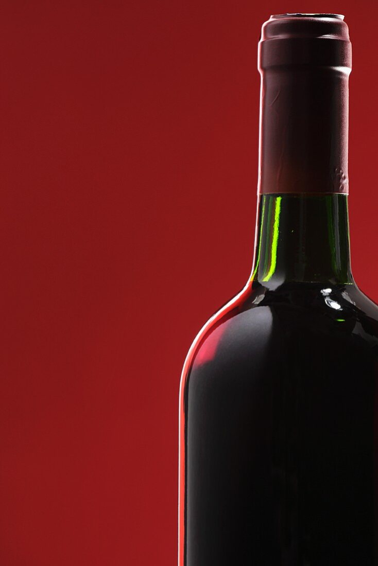 Eine Flasche Rotwein vor rotem Hintergrund