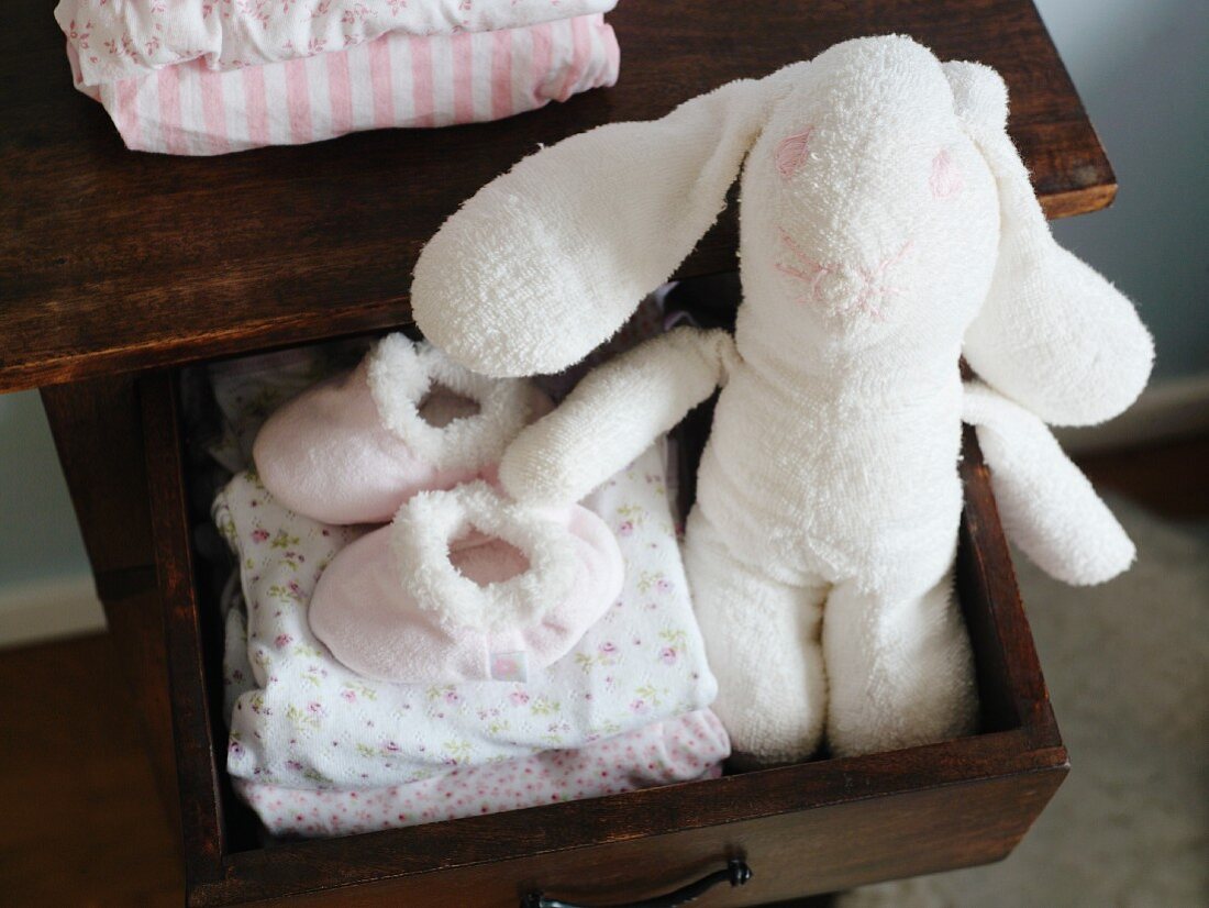 Stuffed rabbit and children's clothes in a drawer