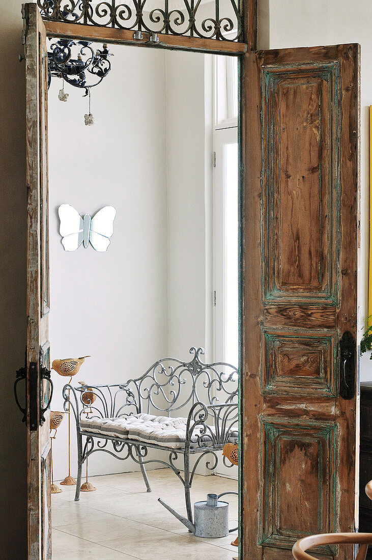 View of metal-framed bench through open, wooden double-doors