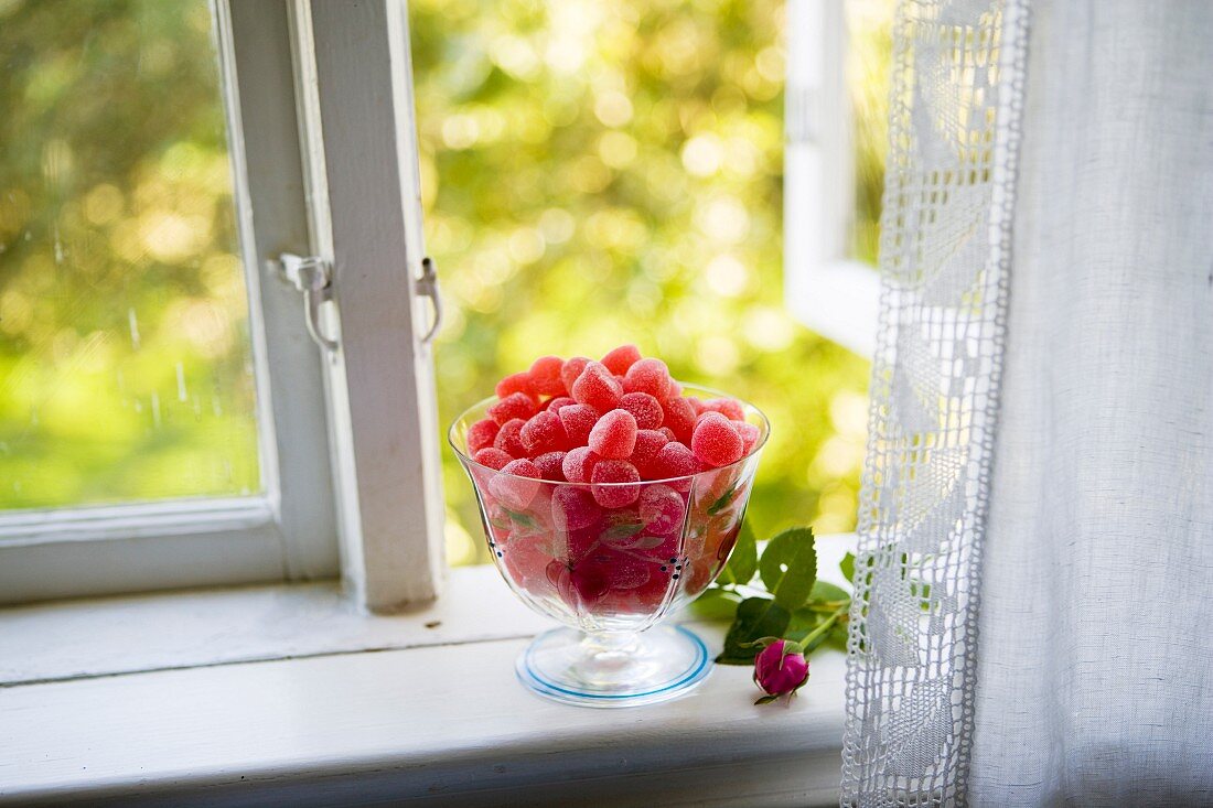 Glass dish with red jelly fruit on a window bench