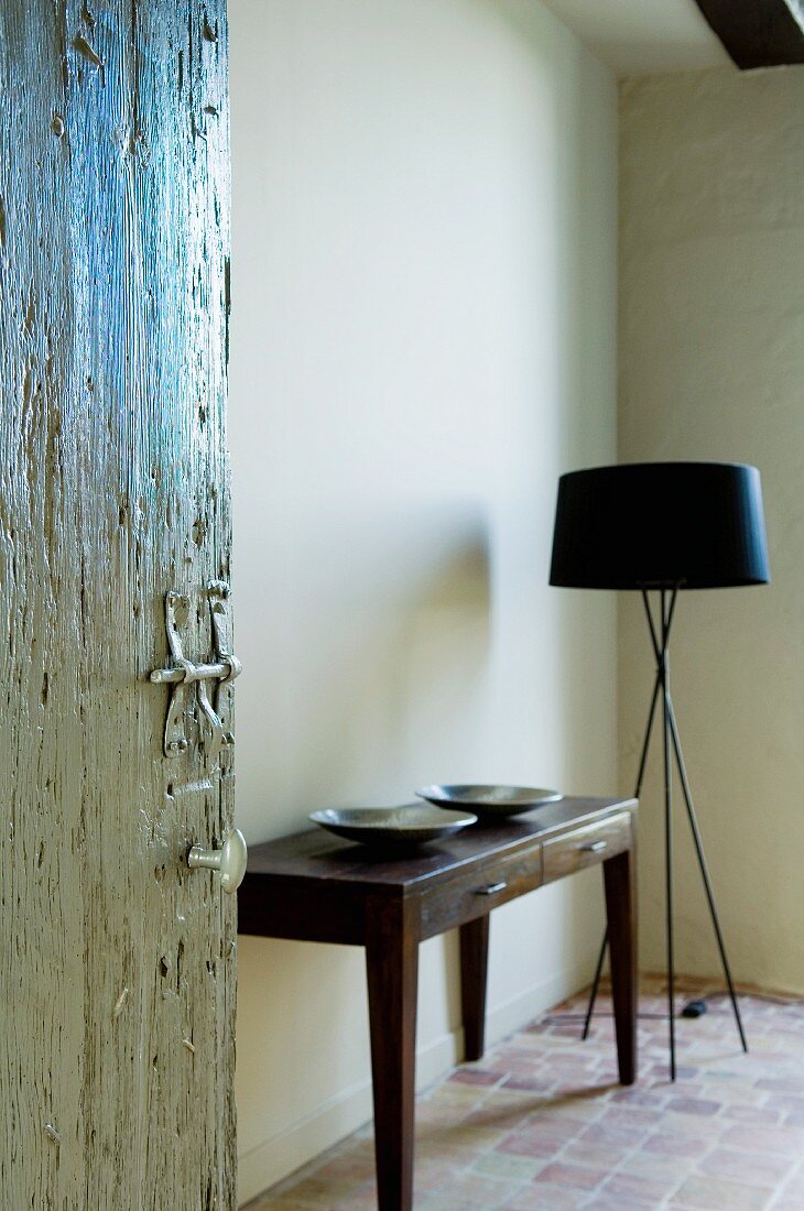 Open interior door showing view of simple console table next to designer standard lamp