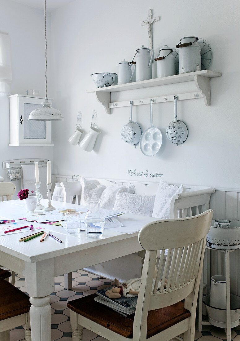 Rustic dining room with white kitchen furniture and collection of vintage milk cans on wall-mounted shelf