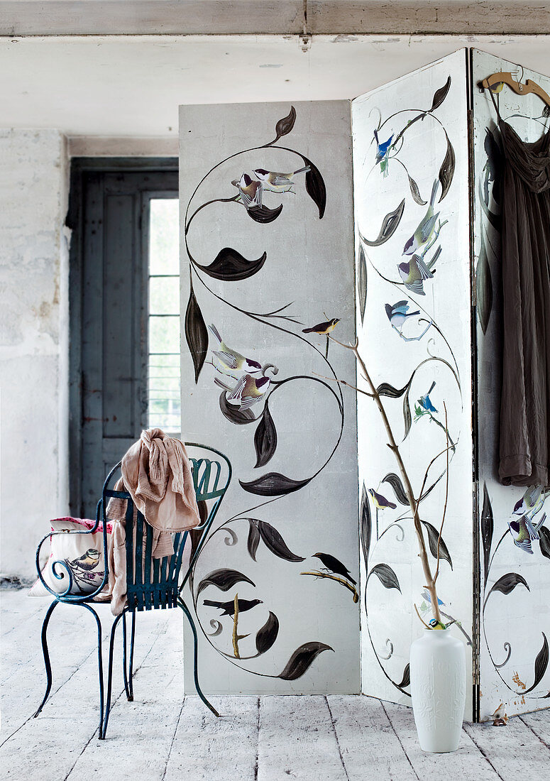 Vintage metal chair next to screen painted with bird motifs