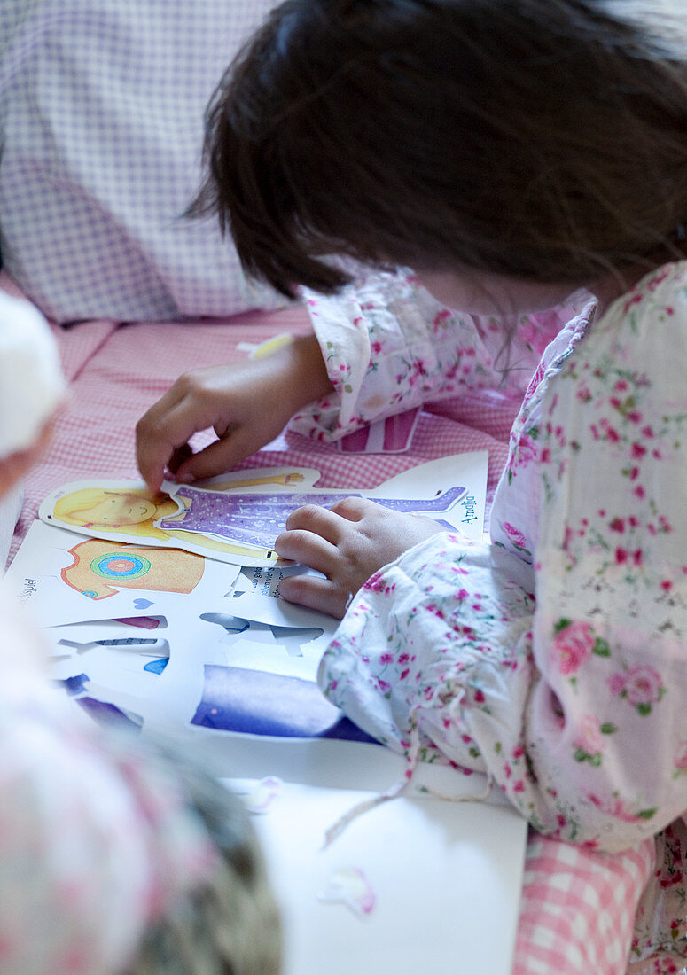 Girl playing with cut-out paper figures