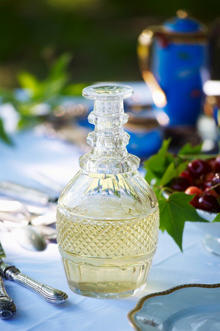A glass carafe of white wine on a garden table